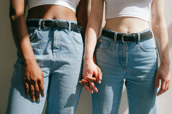 Two women holding hands in matching jeans
