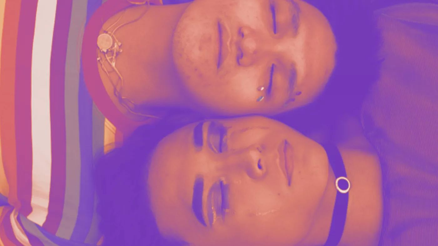 Two men laying side by side with eyes closed.